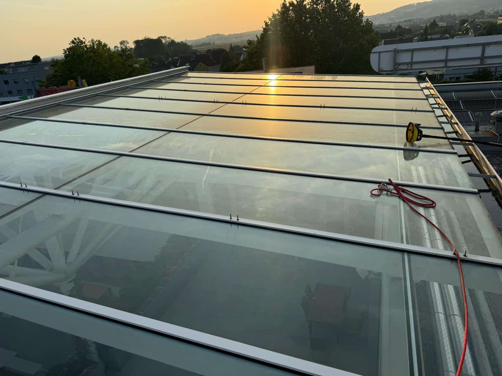 Glasdach mit Reinigungsgeräten bei Sonnenuntergang während der QClean Glasreinigung