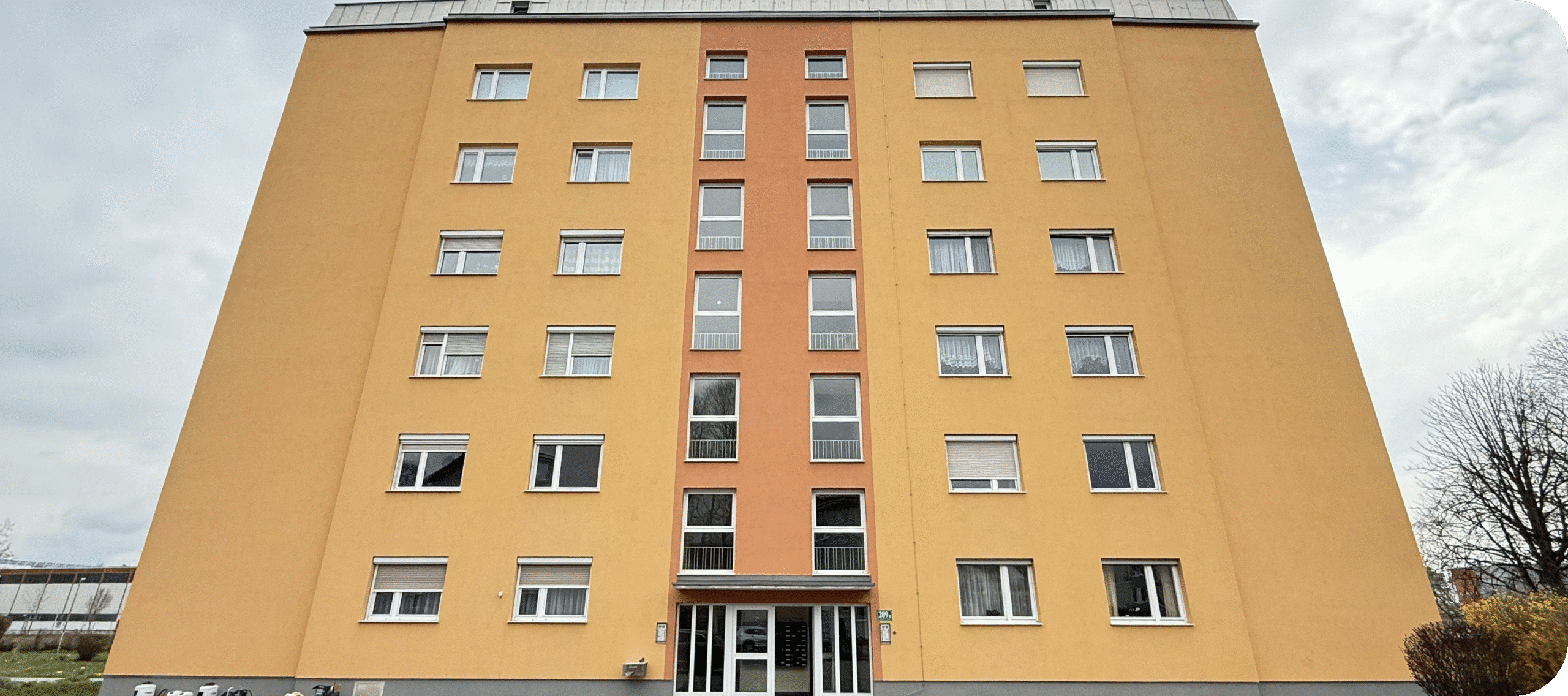 Mehrstöckiges Wohngebäude mit frisch gereinigter gelber Fassade nach der QClean Fassadenreinigung
